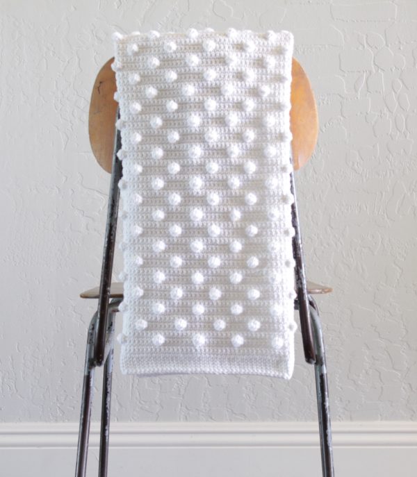 white crochet polka dot blanket hanging over brown chair