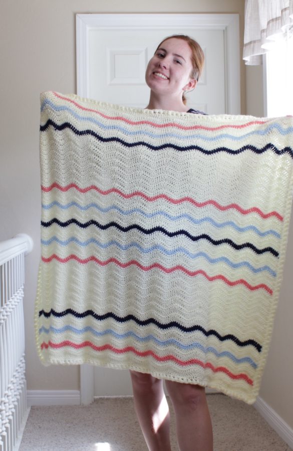 red haired girl holding cream ripple blanket with navy, light blue and pink stripes