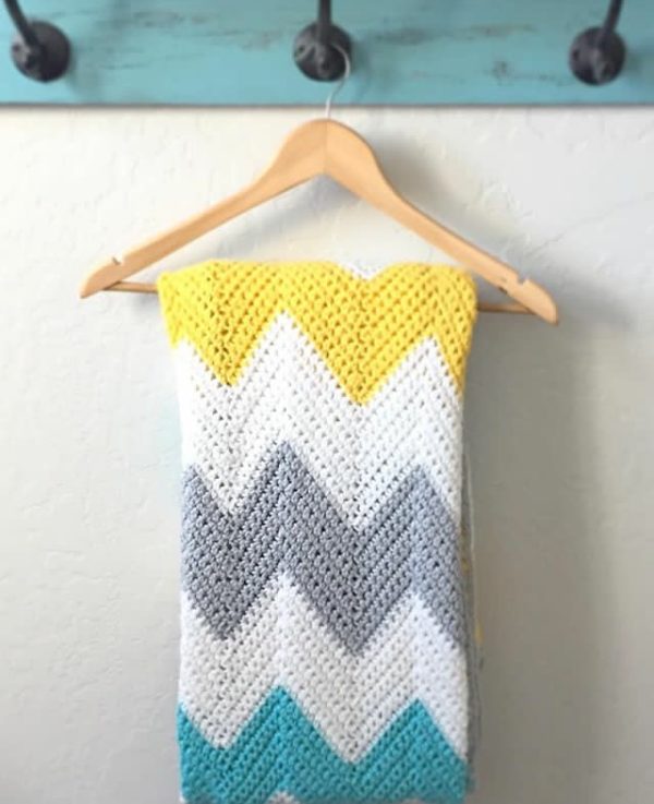 yellow teal gray and white chevron blanket hanging on hanger from teal shelf
