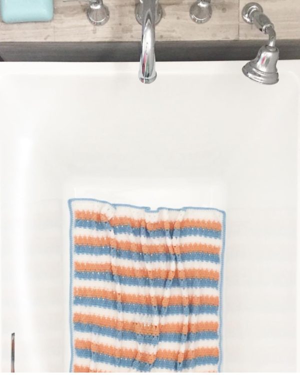 orange blue and white crochet blanket lying in bathtub