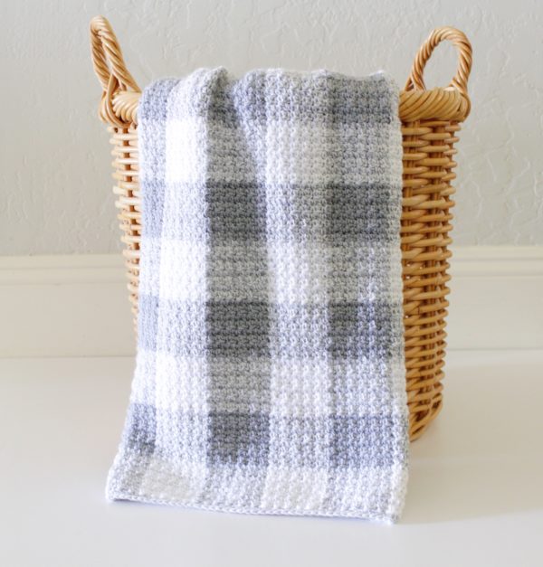 Crochet Grey Gingham Blanket hanging off straw basket