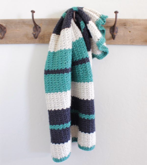 crochet black white and teal spider stitch blanket hanging on hook