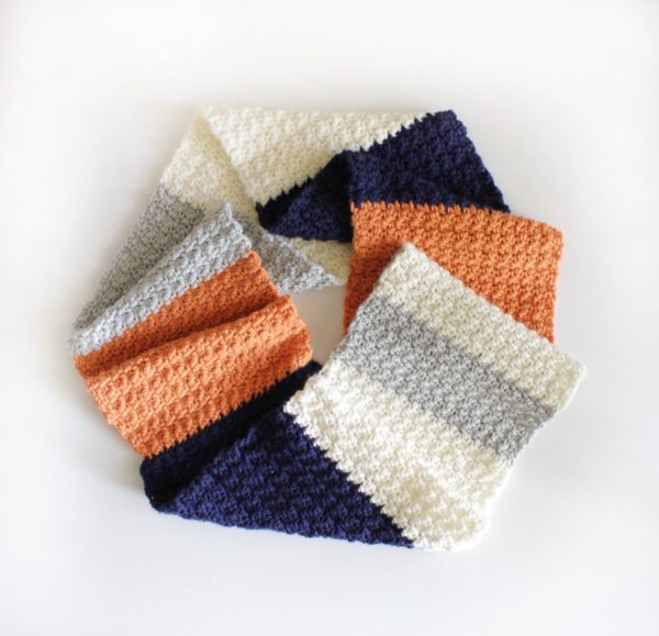 white gray orange and navy crochet griddle stitch scarf laying flat in circle