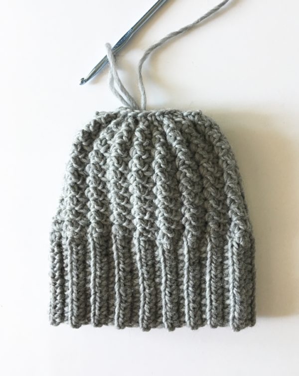 gray crochet sprig stitch bun beanie laying flat on white background