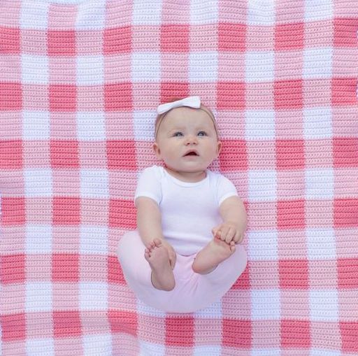 baby laying on pink gingham blanket