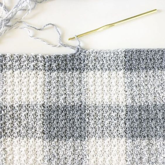 gray gingham crochet blanket in progress with hook on white background