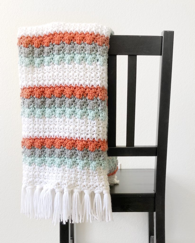 white teal orange gray crochet blanket on chair