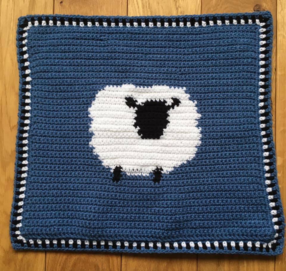 crochet blanket with sheep in middle