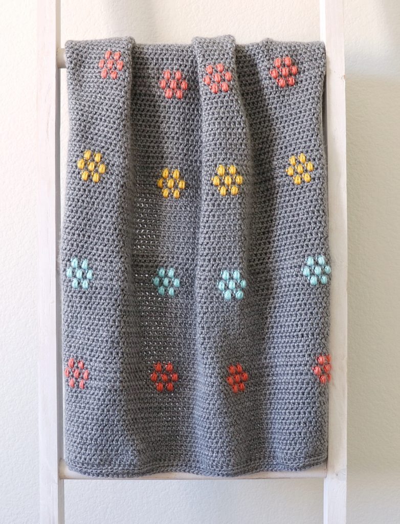 gray crochet blanket with multi color puff flowers