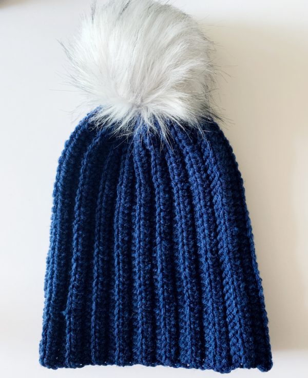 blue crochet hat with white pom pom