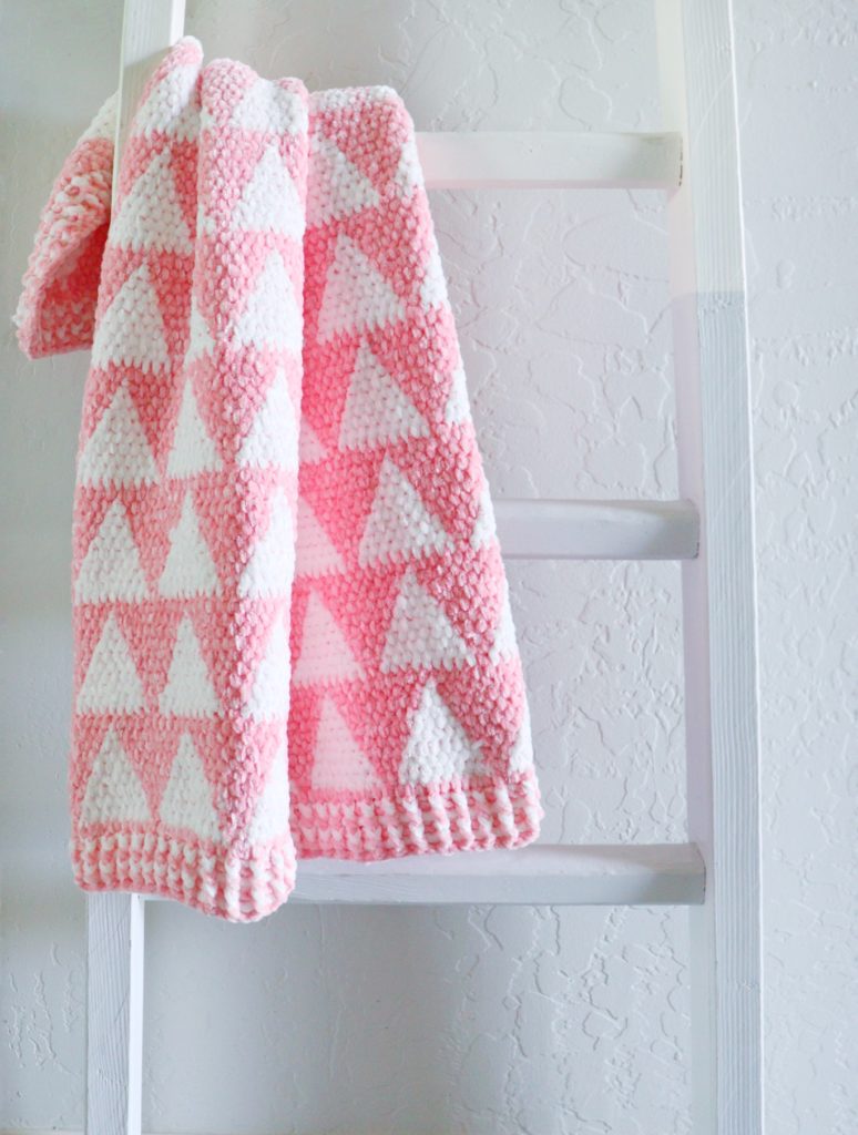 pink and white triangles crochet blanket on ladder