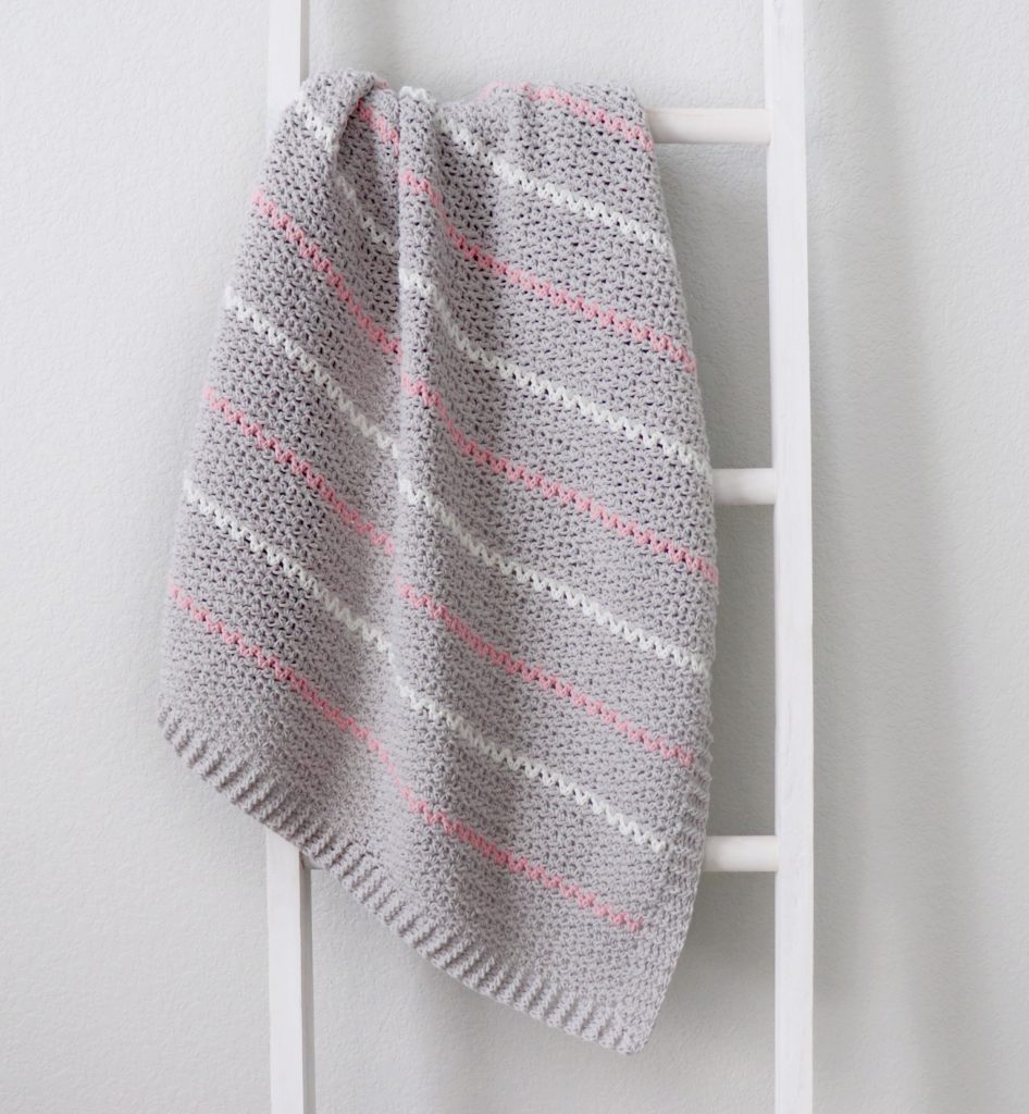 gray white pink crochet blanket on ladder