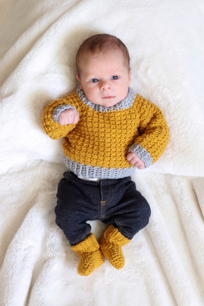 baby wearing crochet sweater and crochet socks