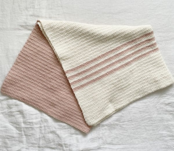 pink and white crochet blanket folded