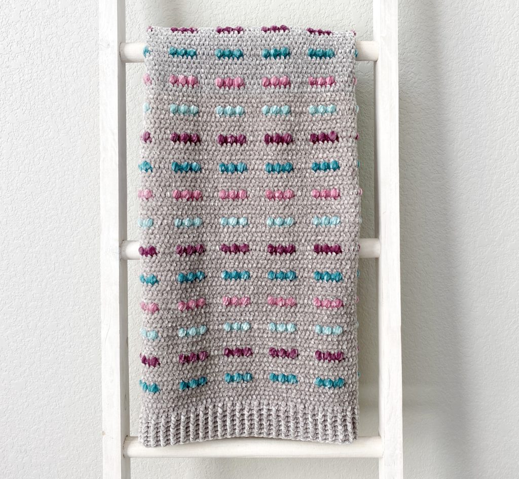 colorful puffs crochet blanket on ladder