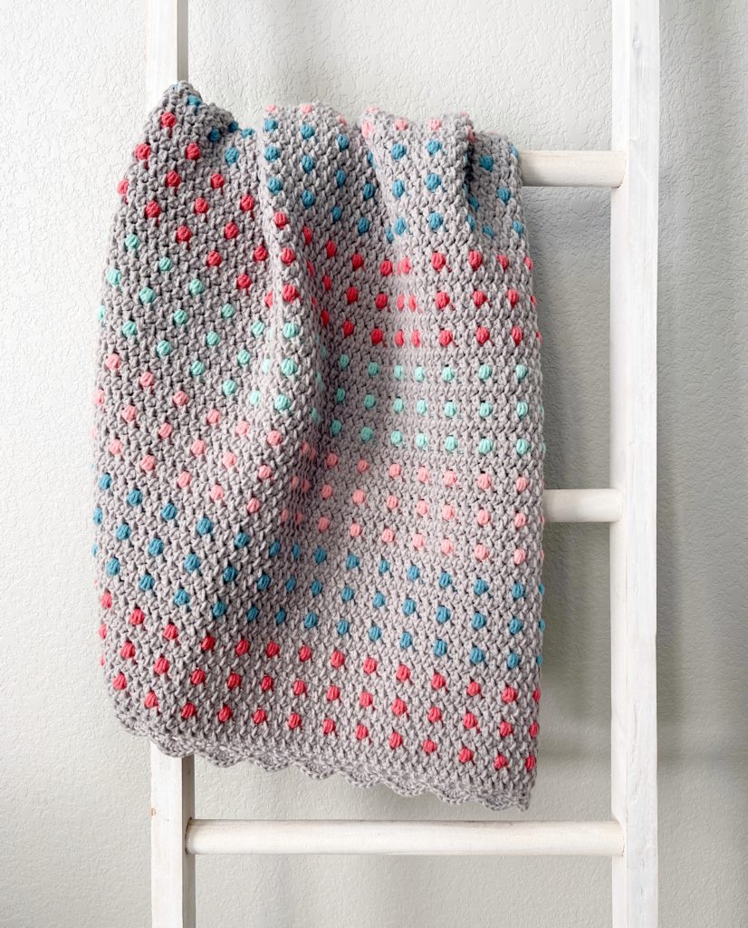 crochet blanket with colorful polka dots hanging on ladder 