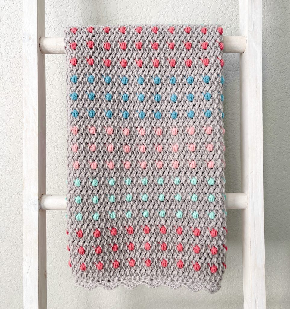 crochet blanket with colorful polka dots hanging straight on ladder