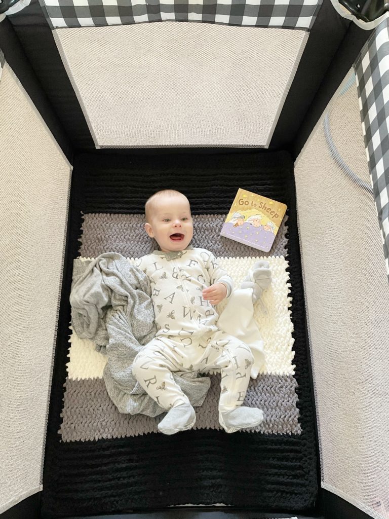 baby laying on crochet blanket in a crib