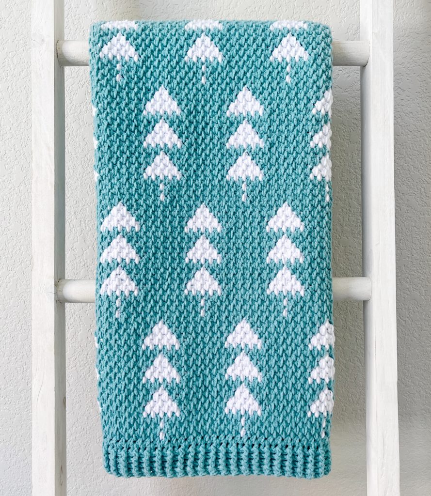 crochet teal blanket with white trees hanging straight from white ladder