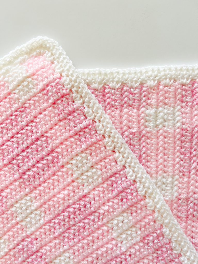 close up of white border of crochet pink plaid blanket