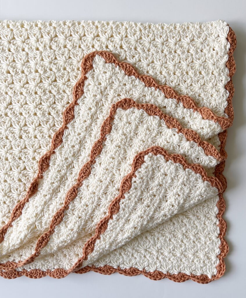 cream crochet flower blanket with orange border corners folded