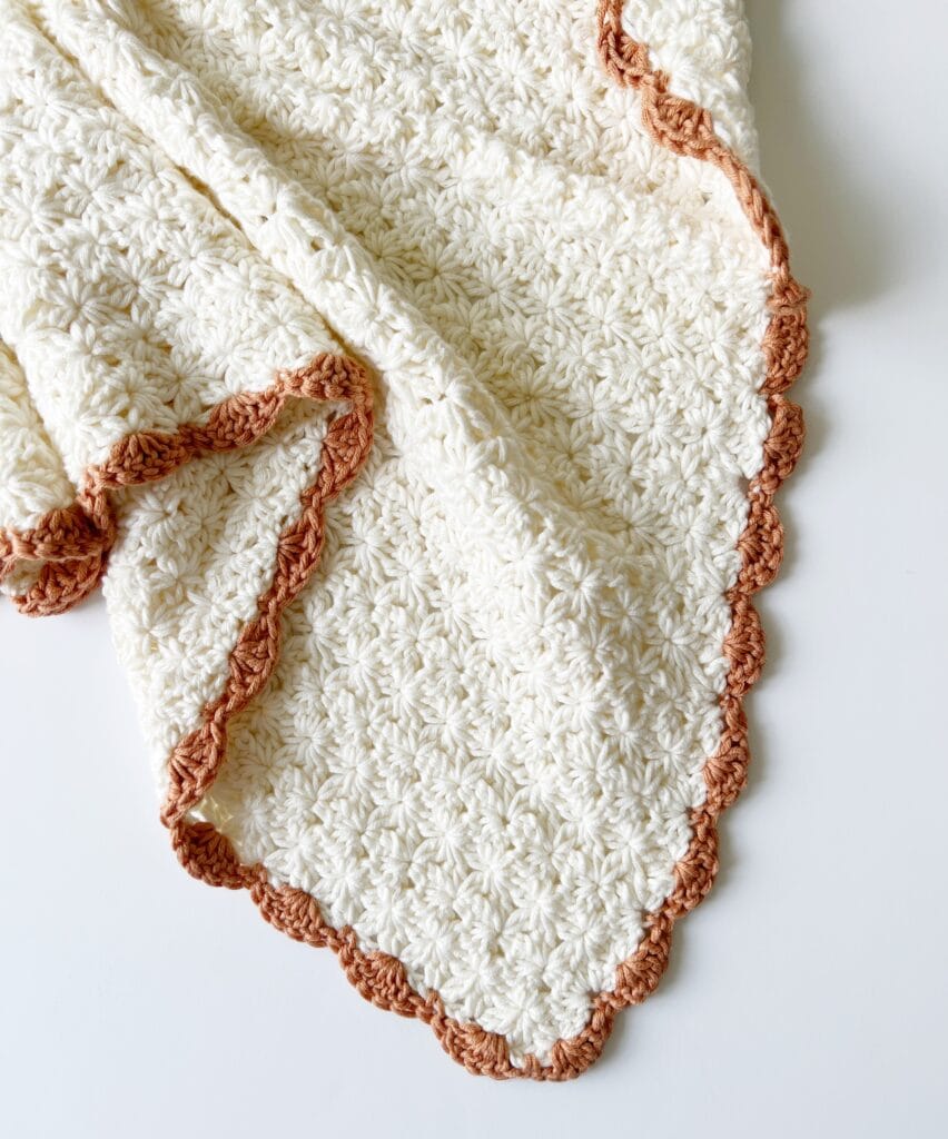 corner of cream flower blanket with orange shell border