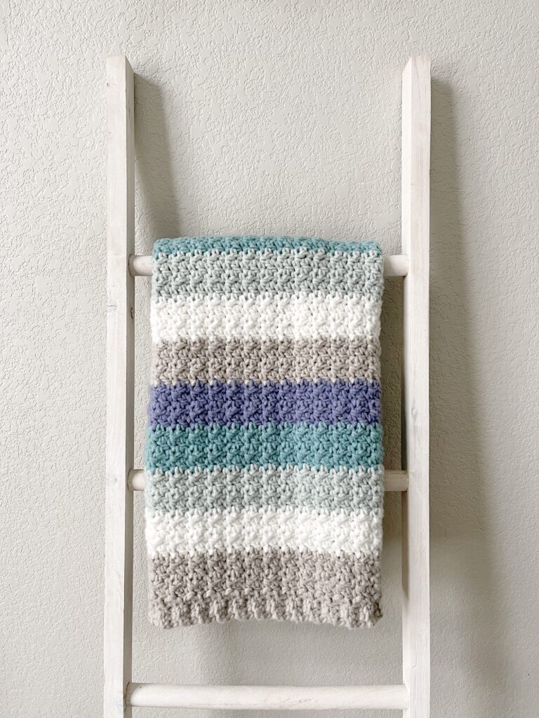 crochet blanket with gray and blue stripes on ladder