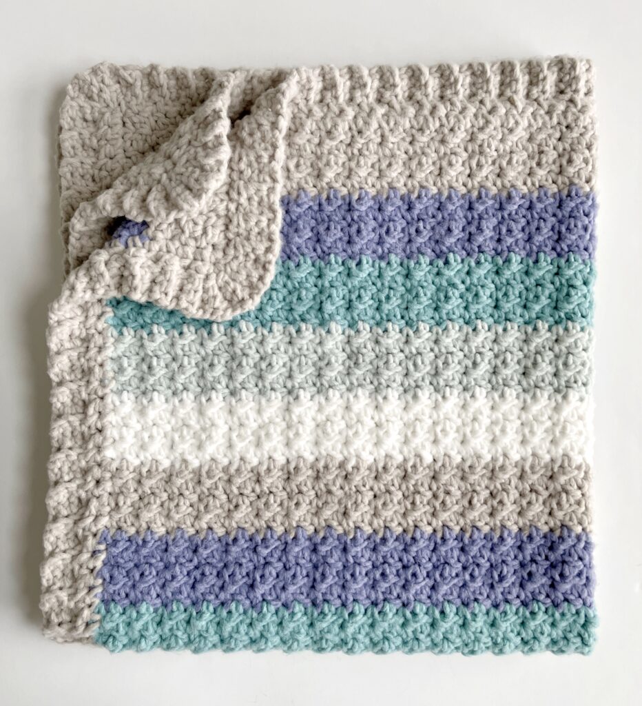 crochet blanket with gray and blue stripes folded corner