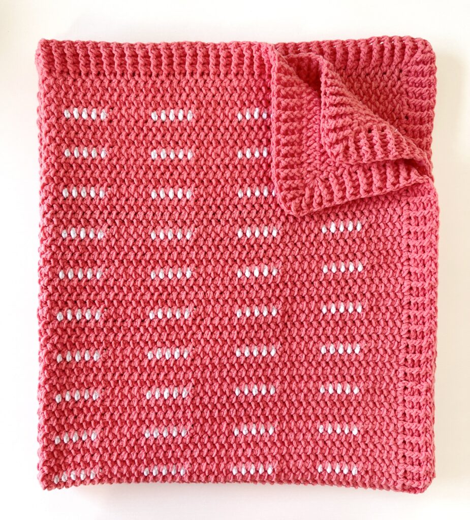 pink and white crochet blanket folded