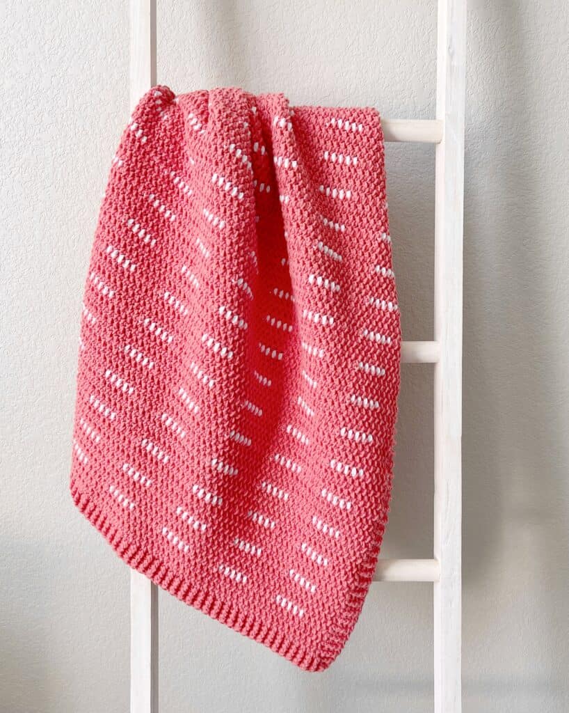 pink and white crochet blanket on ladder