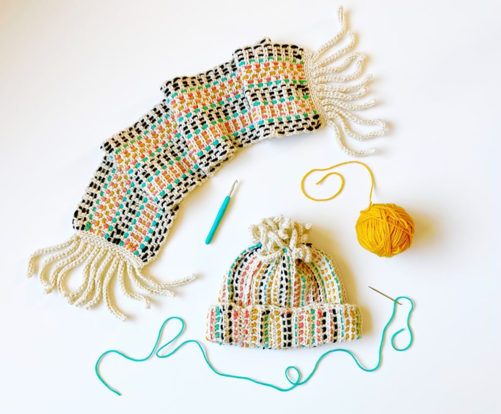 scarf, hat, yarn ball and crochet hook on table 