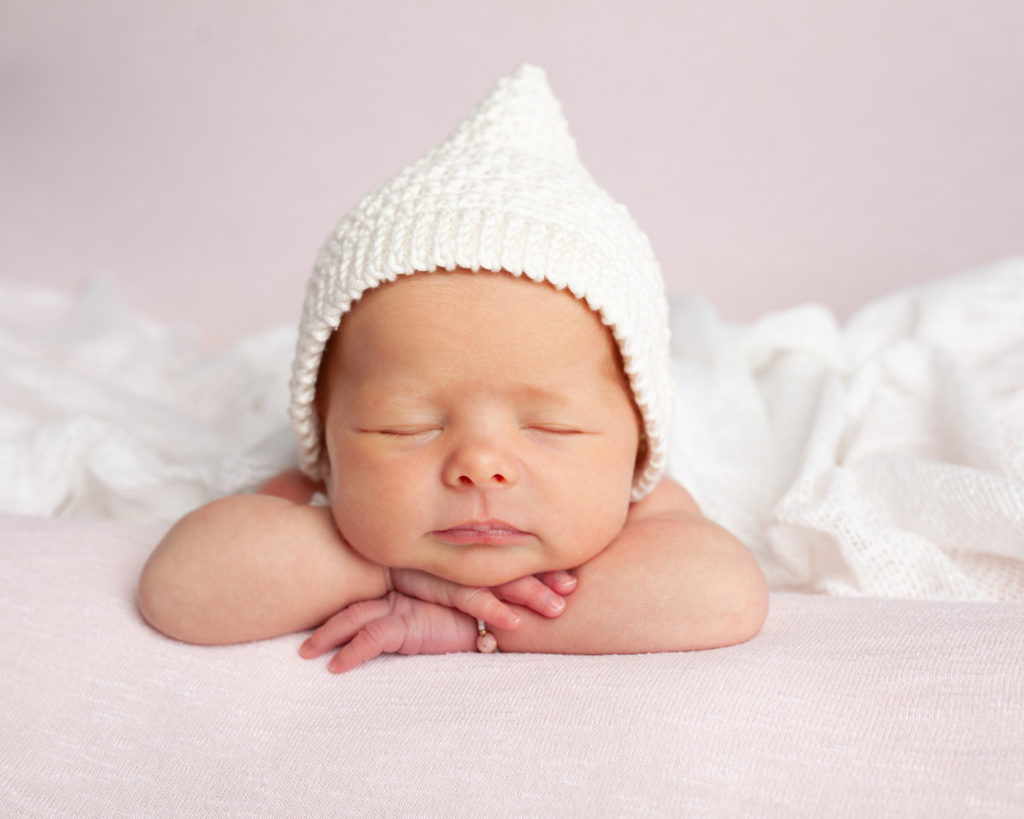 newborn with hands under chin