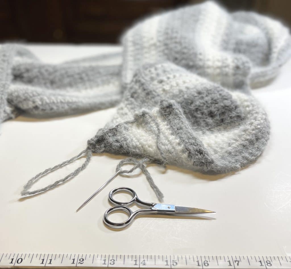 scarf on table with threading needle, scissors, tape measure