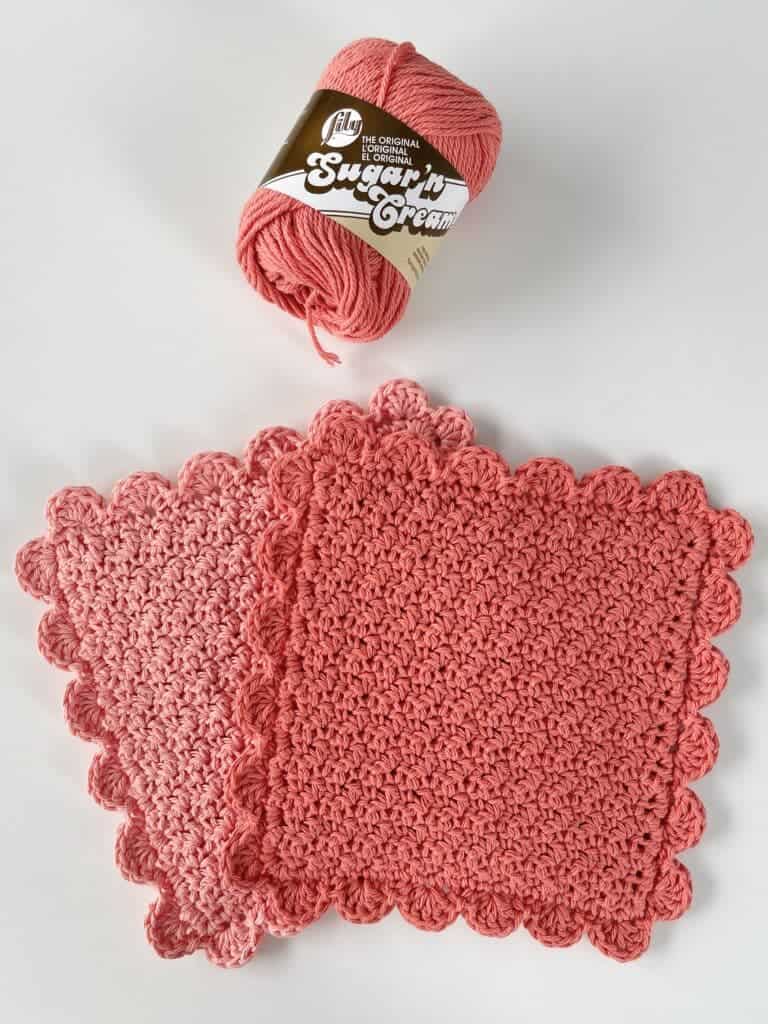 two hot pads on table with skein of yarn