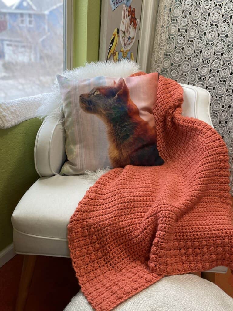 Blanket on white chair with pillow. 