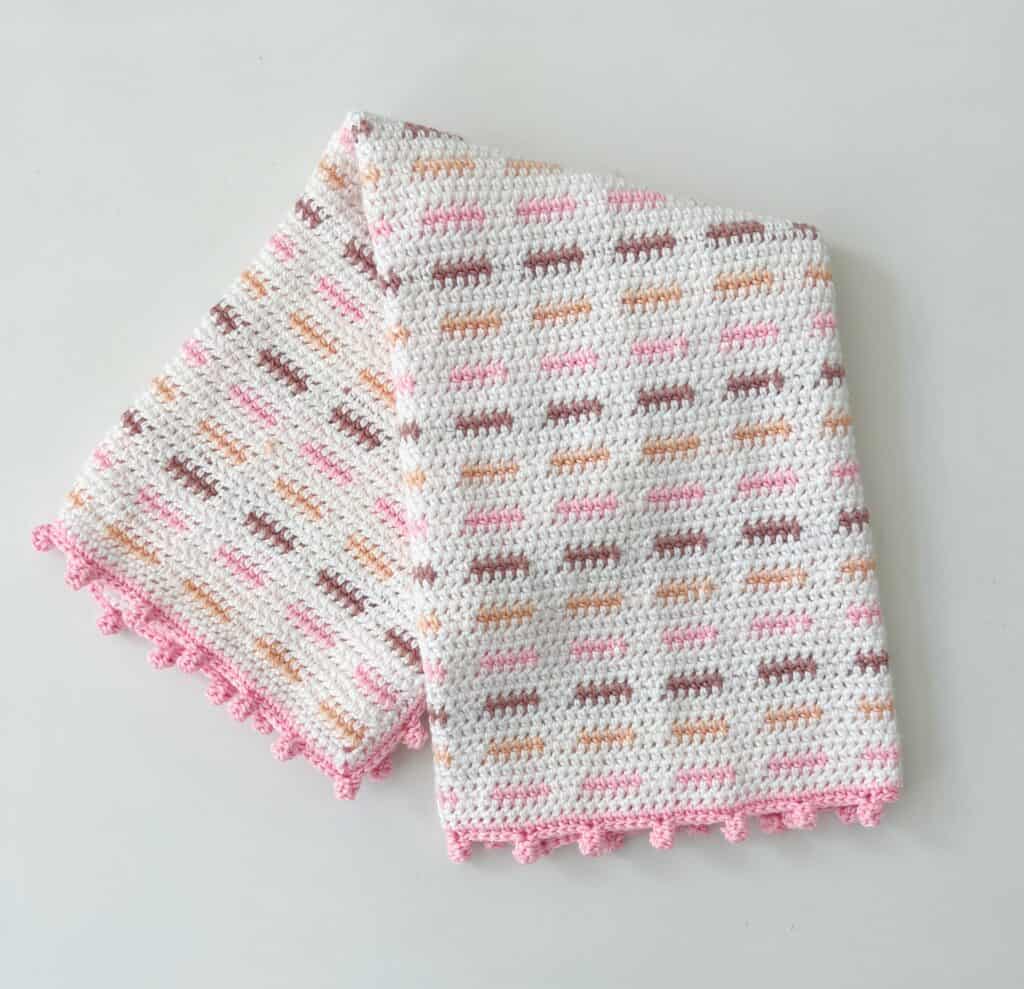 crochet baby blanket white with pink trim small dashes of color in peach pink and dusty rose