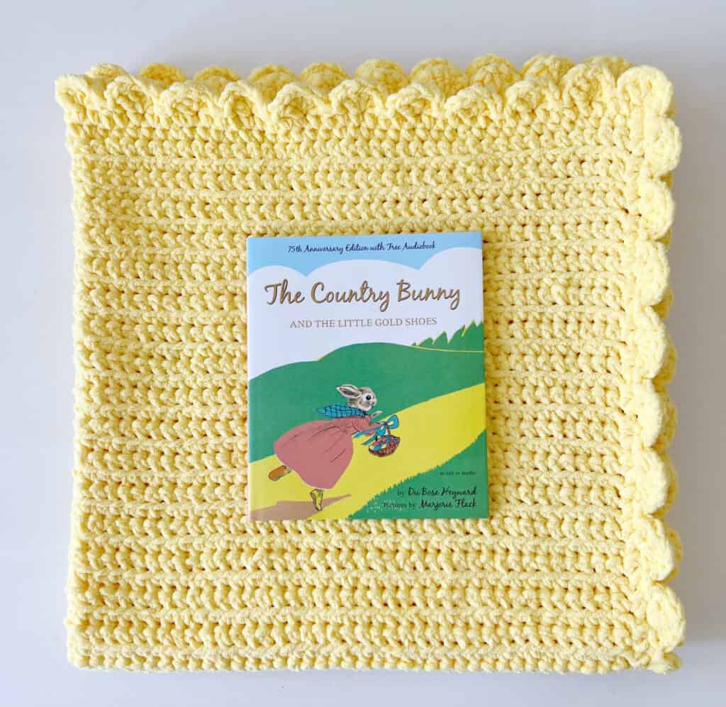 A book laying on top of yellow crochet blanket