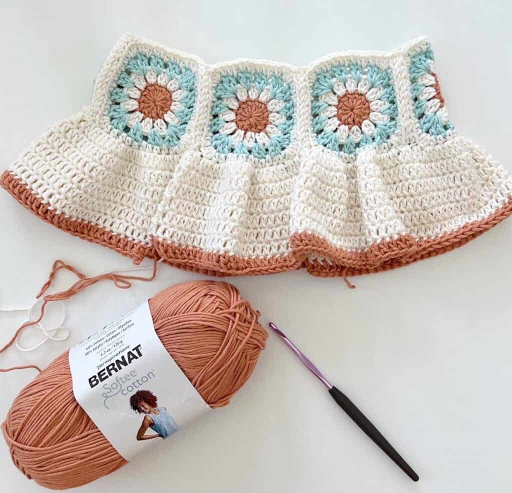 crochet baby dress, yarn skein, and crochet hook