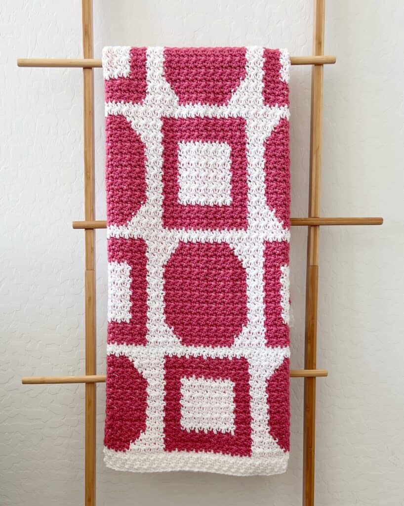 pink and white crochet blanket on ladder