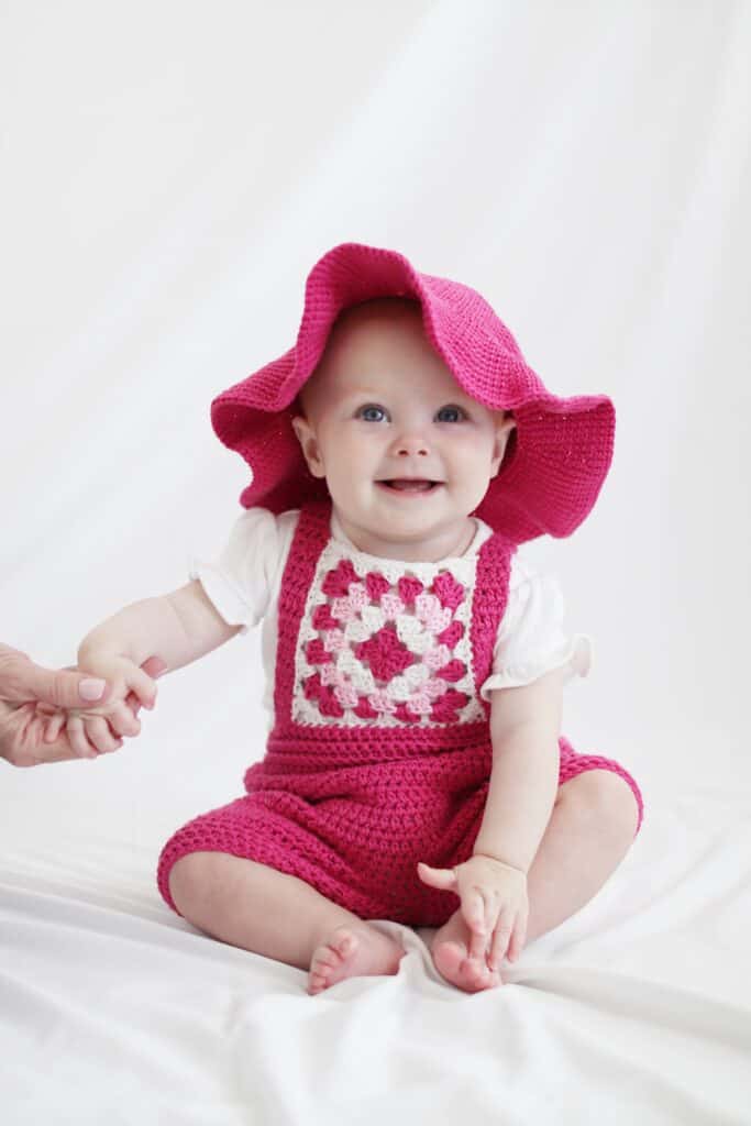 Baby girl wearing crochet granny square romper with crochet sun hat