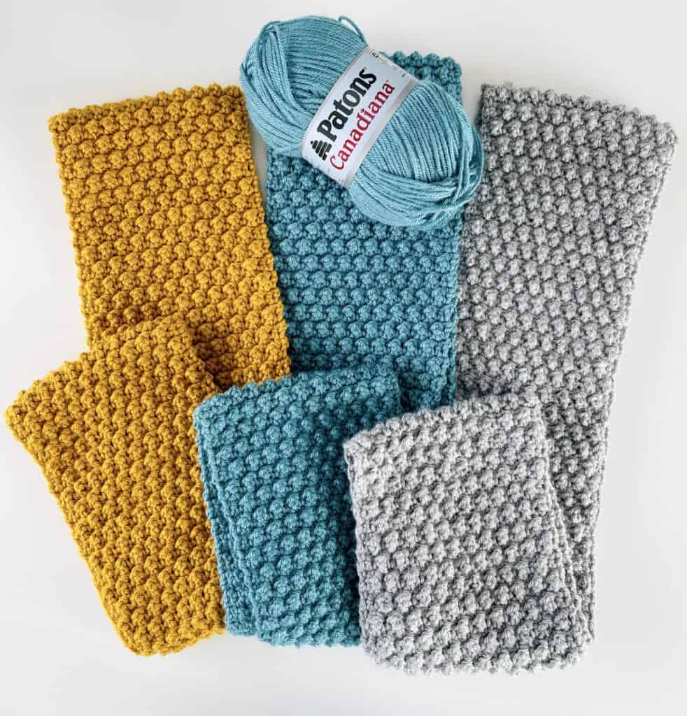 Yellow scarf, blue scarf, gray scarf, blue skein of yarn
