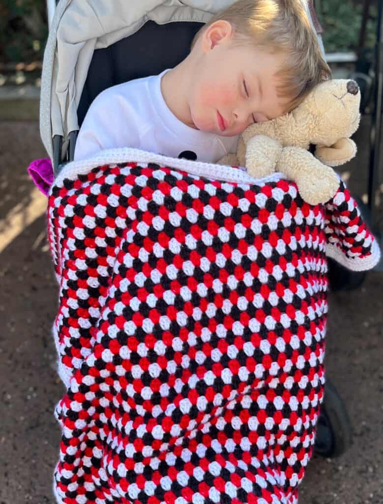 baby boy sleeping in stroller with doggie and crochet blanket