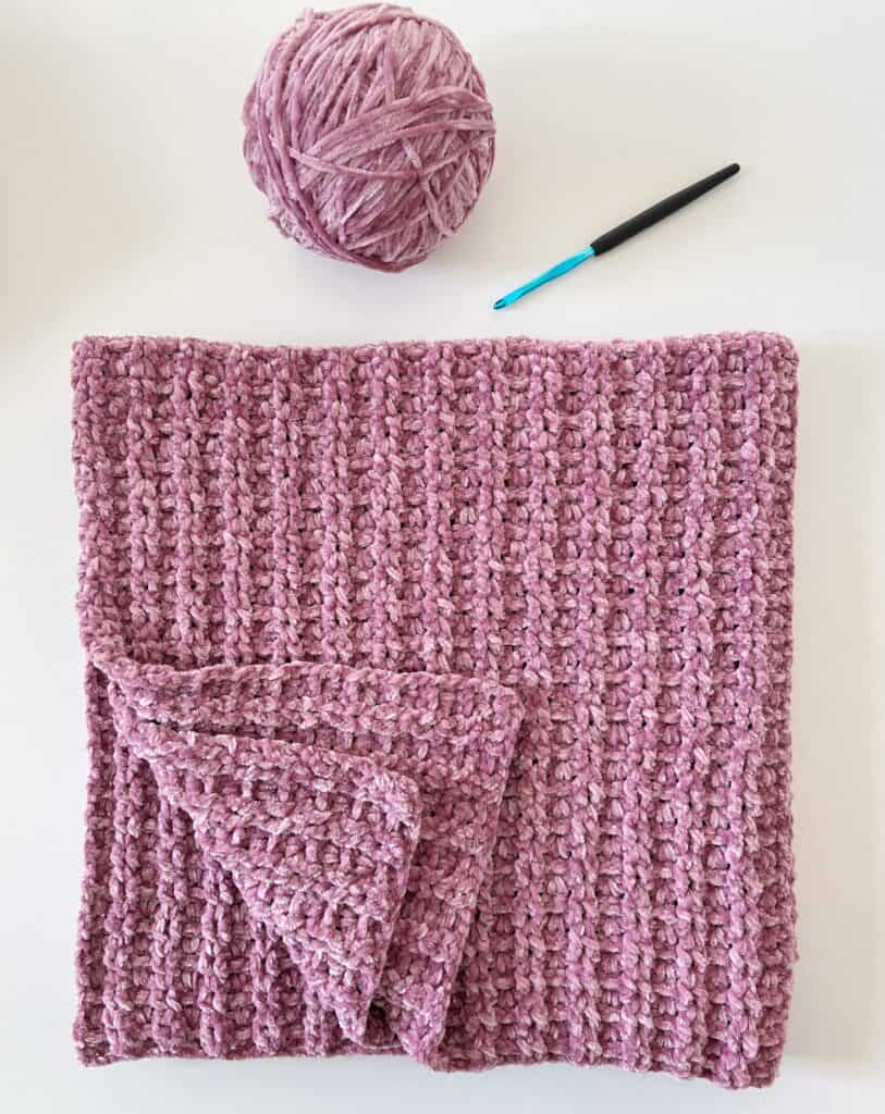 Crochet blanket with velvet yarn, ball of yarn and crochet hook