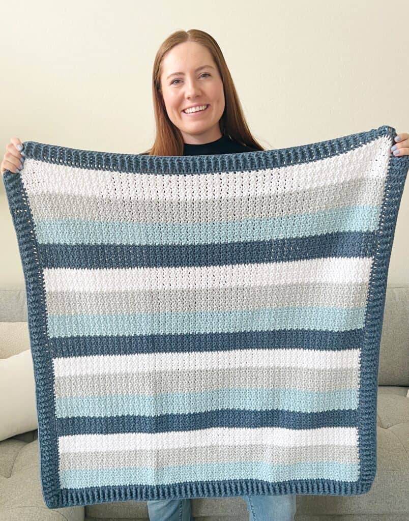 Annie holding blue crochet baby blanket