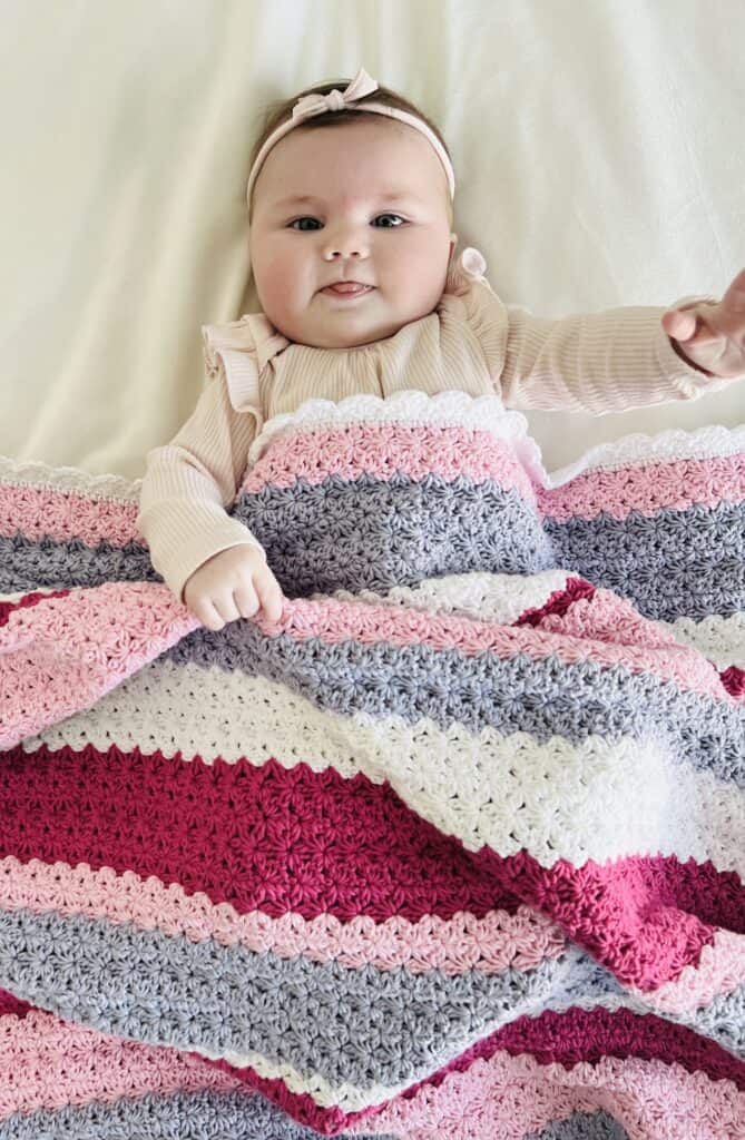 Baby Nora cuddling with Crochet Mixed Stripe Flower Blanket